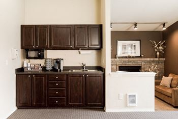 a kitchen with dark cabinets and a living room with a fireplace